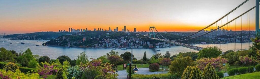 A sunset view looking over the city of Istanbul with the river in the forefront with a bridge over it.