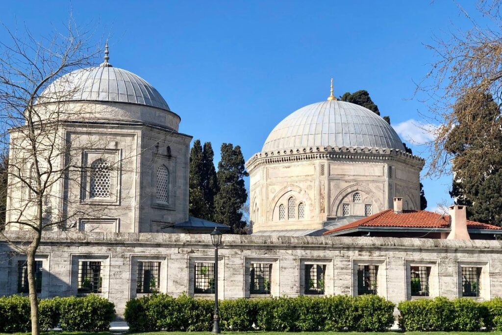 Stone building with two domes with gardens infront
